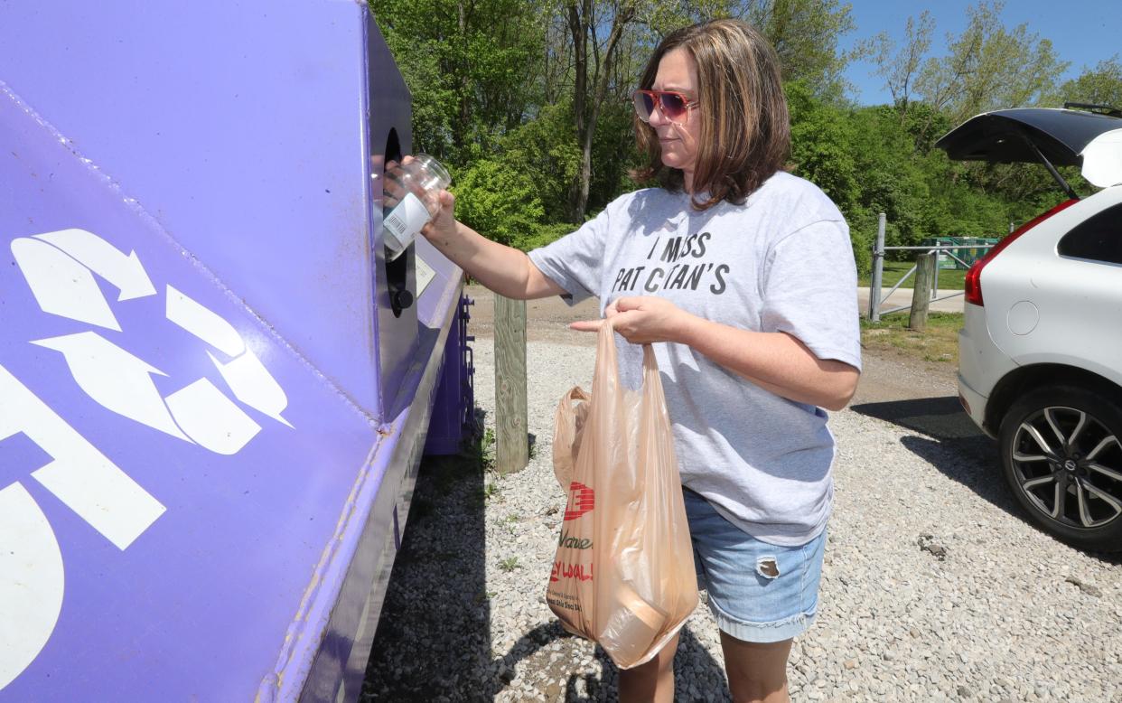 Highland Square resident Cheryl Hopkins deposits glass into the recycling bin located at the Akron dog park at 499 Memorial Parkway on Thursday.