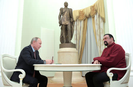 Russia's President Vladimir Putin (L) holds a Russian passport before presenting it to U.S. actor Steven Seagal during a meeting at the Kremlin in Moscow, Russia, November 25, 2016. Sputnik/Kremlin/Alexei Druzhinin via REUTERS.