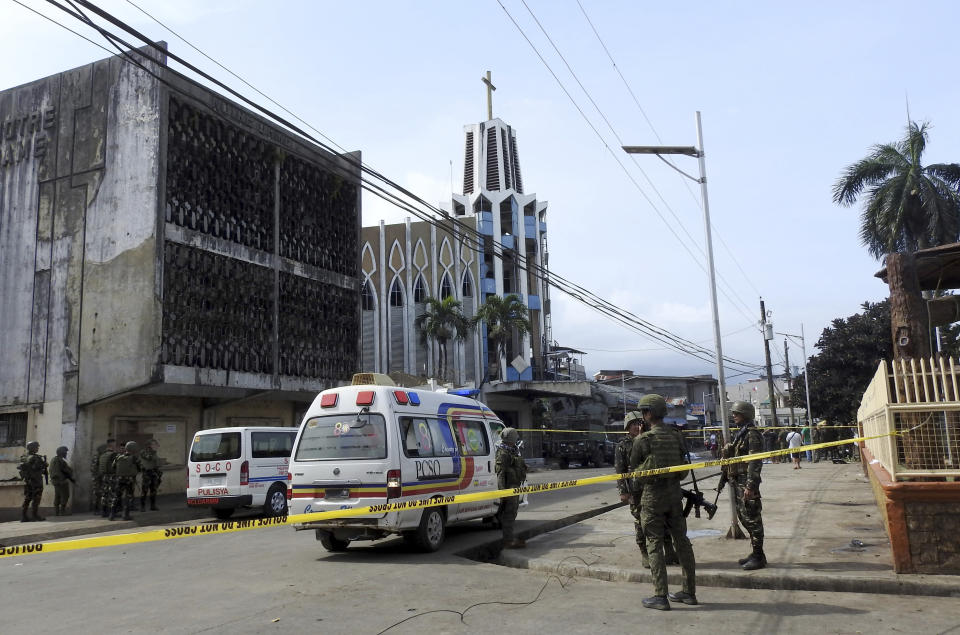 FILE - In this Jan. 27, 2019, file photo, police investigators and soldiers attend the scene after two bombs exploded outside a Roman Catholic cathedral in Jolo, the capital of Sulu province in southern Philippines. Two suicide attackers detonated bombs during a Mass in a Roman Catholic cathedral on the largely Muslim island of Jolo, killing 23 and wounding about 100. (AP Photo/Nickee Butlangan, File)