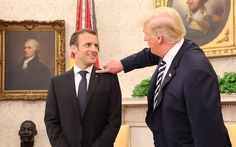 Donald Trump pretends to brush a bit of dandruff off Emmanuel Macron's shoulder - Credit: LUDOVIC MARIN/AFP/Getty Images