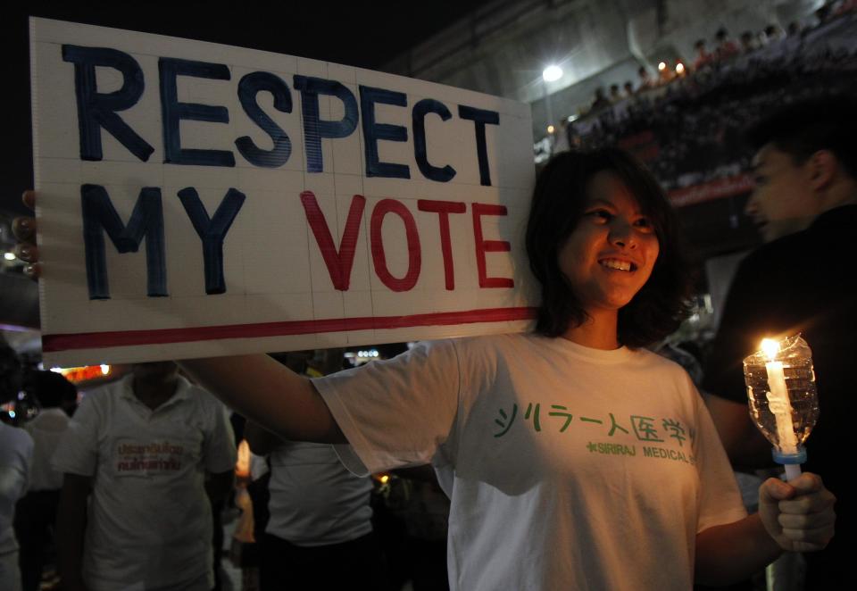 A woman holds a candle and a placard during an anti-violence campaign in central Bangkok January 10, 2014. Thailand on Friday played down talk of a military coup ahead of a planned "shutdown" of the capital next week by protesters trying to overthrow Prime Minister Yingluck Shinawatra and said life would go on much as normal. REUTERS/Chaiwat Subprasom (THAILAND - Tags: POLITICS CIVIL UNREST)