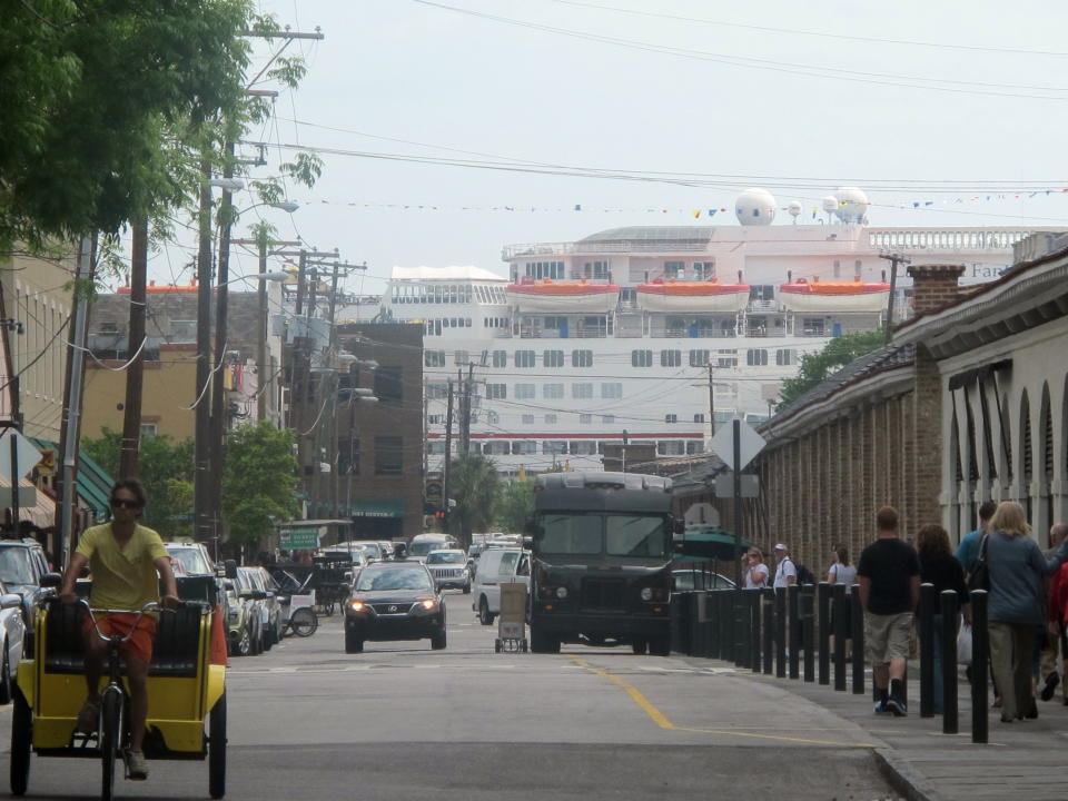 In this April 18, 2012, photo, the Carnival Fantasy towers over the end of Market Street in Charleston, S.C. For more than two years the debate over cruise ships calling year-round in Charleston has raged with a state Supreme Court case, conflicting economic studies and rhetoric. Preservationists cite the threat to the city's historic character while cruise supporters say the industry is being administered appropriately and provides needed jobs and a boost to the local economy. (AP Photo/Bruce Smith)