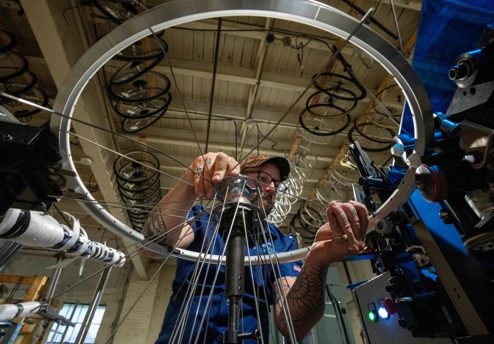 Seed laces a bicycle rim in Detroit at Detroit Bikes.