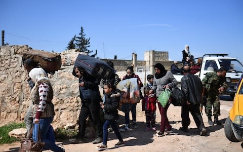 Civilians fleeing Afrin after Turkey said its army and allied rebels surrounded the Kurdish city in northern Syria, walk towards a Kurdish and Syrian pro-regime forces check point  - Credit: AFP