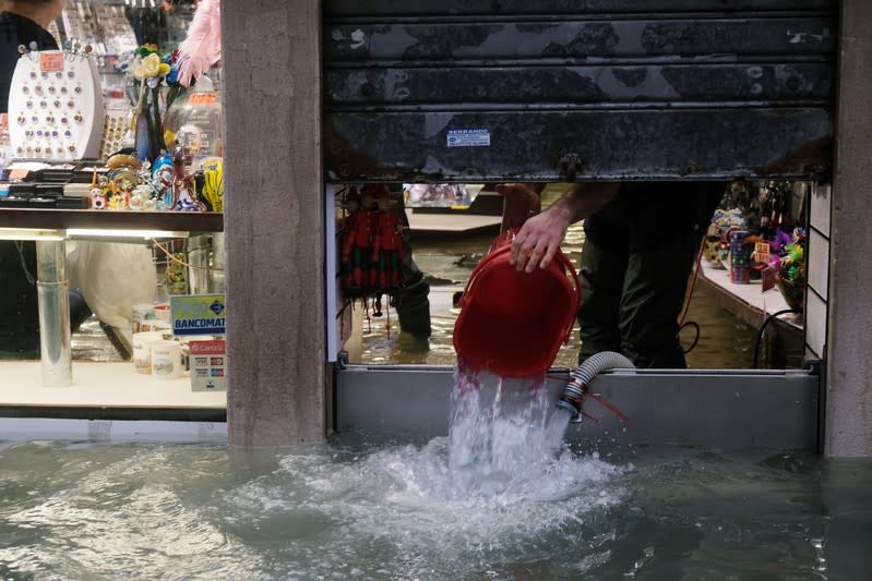 A man removes water from the flooded shop during a period of seasonal high water in Venice