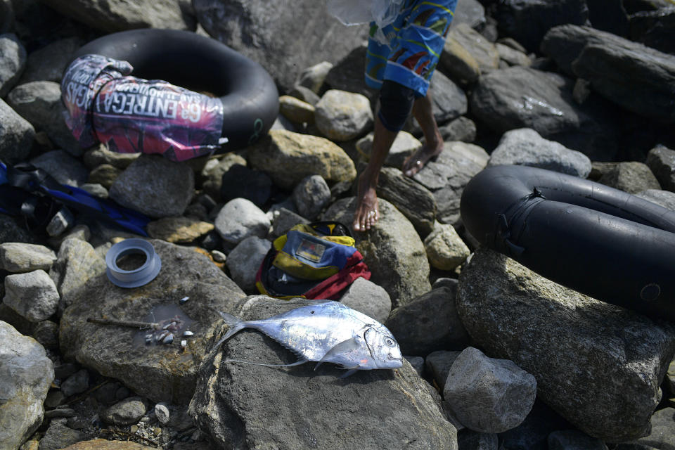 Eric Mendez, a 40-year-old bricklayer by trade, prepares to clean a sunfish, part of his catch of the day, on the shore of Playa Escondida in La Guaira, Venezuela, Friday, Aug. 14, 2020. A small but growing number of people in the coastal town have turned to the sea for substance since the COVID-19 pandemic has shut down the Caribbean nation’s already failing economy. (AP Photo/Matias Delacroix)