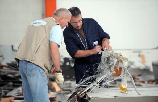 An investigator (L) from the French bureau leading an investigation into an Air France crash inspects debris from the crash in Toulouse, southern France