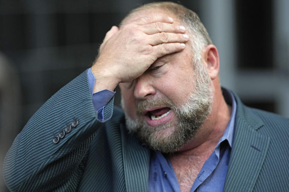 Right-wing conspiracy theorist Alex Jones wipes his forehead as he speaks to the media after arriving at the federal courthouse for a hearing in front of a bankruptcy judge Friday, June 14, 2024, in Houston. The judge is expected to rule on whether to liquidate Jones' assets to help pay the $1.5 billion he owes for his false claims that the Sandy Hook Elementary School shooting was a hoax. (AP Photo/David J. Phillip)