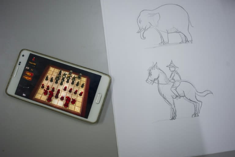 illustrations displayed next to the mobile phone of a developer testing a Myanmar chess app at the Myplay software house in Yangon