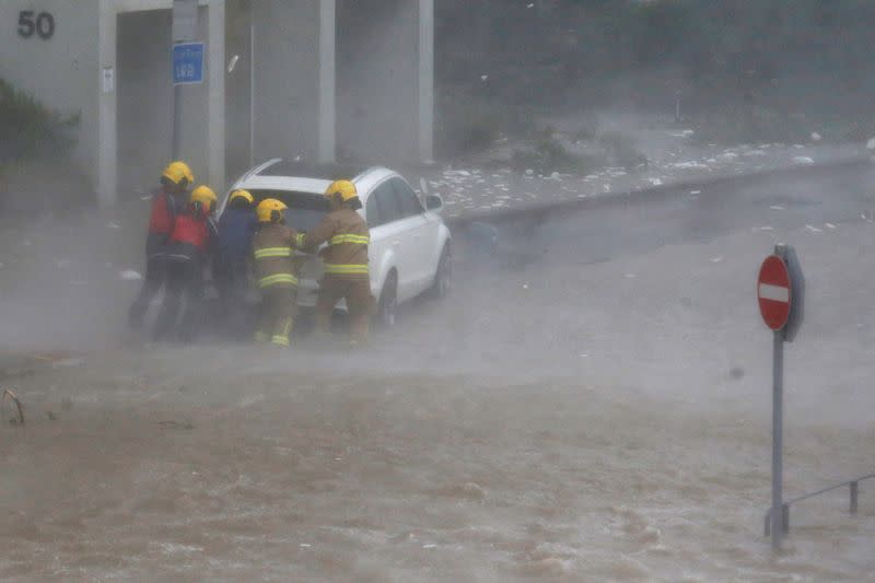 FILE PHOTO: Firefighters push a car in flooded waters as high waves hit the shore at Heng Fa Chuen, a residental district near the waterfront, as Typhoon Mangkhut slams Hong Kong