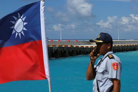 FILE PHOTO: A member of the Taiwanese Coast Guard stands guard next to a Taiwanese flag on Itu Aba, which the Taiwanese call Taiping, at the South China Sea, November 29, 2016. REUTERS/J.R Wu