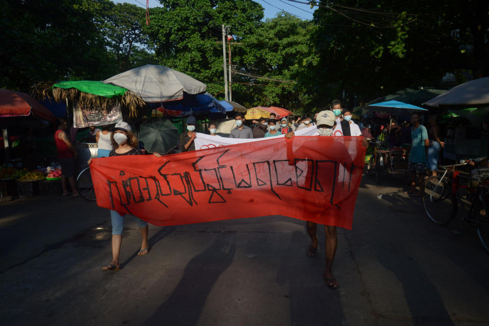 FILE - People march to protest against the February military takeover, in Yangon, Myanmar, on April 11, 2021. The banner reads, "Absolutely no dictatorship." Japanese video journalist Toru Kubota has been detained by security forces in Myanmar while covering a protest against military rule in the country’s largest city, pro-democracy activists said Sunday, July 31, 2022. (AP Photo, File)