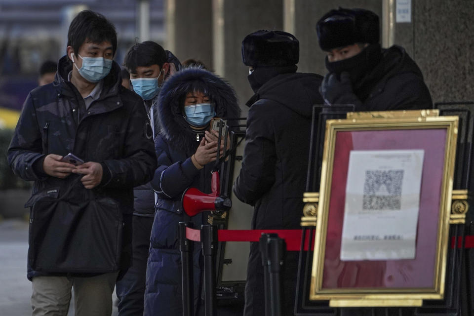 People wearing face masks to help curb the spread of the coronavirus use smartphones to scan their health code before entering an office building in Beijing, Tuesday, Jan. 12, 2021. Lockdowns have been expanded and a major political conference postponed in a province next to Beijing that is the scene of China's most serious recent COVID-19 outbreak. (AP Photo/Andy Wong)