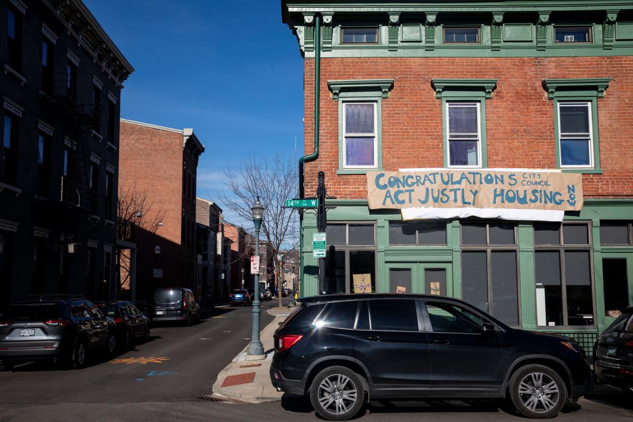 A sign that reads, "Congratulations City Council, Act Justly, Housing Now," hangs on a building on 14th Street, adjacent to Washington Park in Over-the-Rhine where the inaugural session of the city council is being held on Tuesday, Jan. 4, 2022.