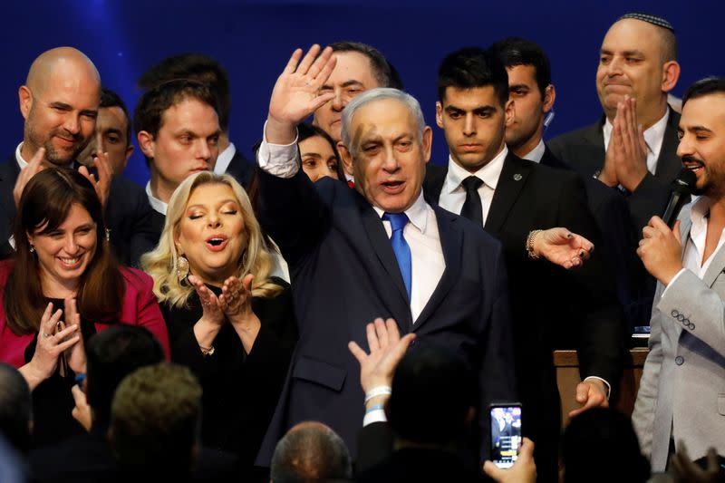 Israeli Prime Minister Benjamin Netanyahu stands next to his wife Sara as he waves to supporters following the announcement of exit polls in Israel's election at his Likud party headquarters in Tel Aviv