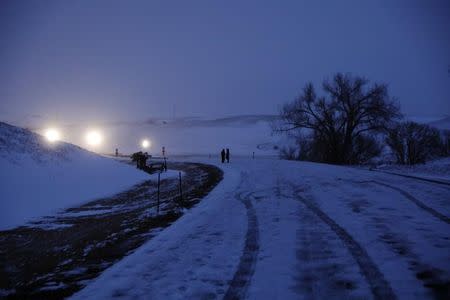 A couple stands lit by police lights near Backwater Bridge just outside of the Oceti Sakowin camp during ongoing demonstrations against the Dakota Access pipeline near the Standing Rock Indian Reservation, near Cannon Ball, North Dakota, U.S., December 1, 2016. REUTERS/Lucas Jackson