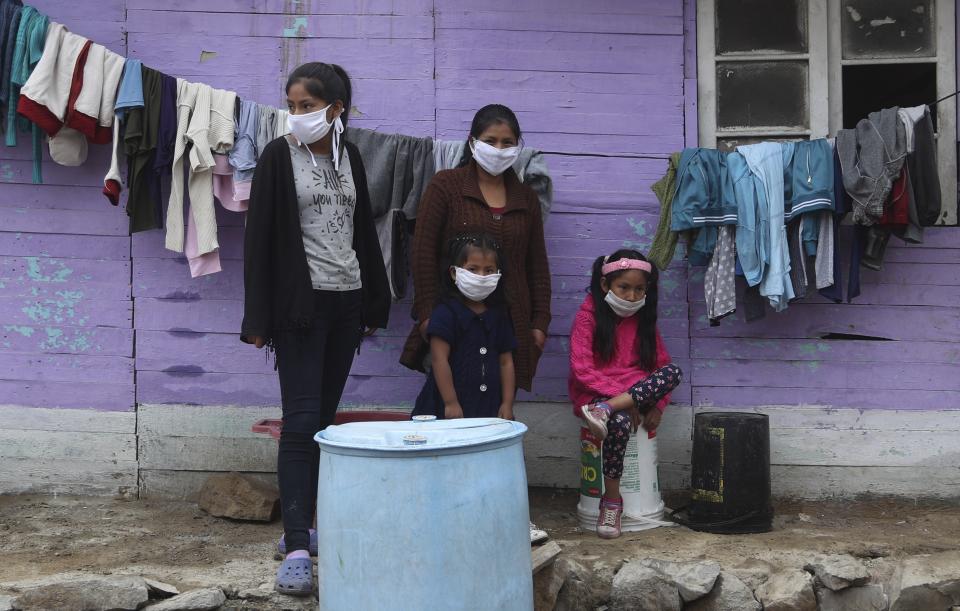 Wearing masks to prevent the spread of the new coronavirus, the Sanchez sisters Silvana, left, Maria, second left back, Luisa, second right front, and Brittany stand in from of their home in Puente Piedra shantytown on the outskirts of Lima, Peru, Monday, June 1, 2020. (AP Photo/Martin Mejia)