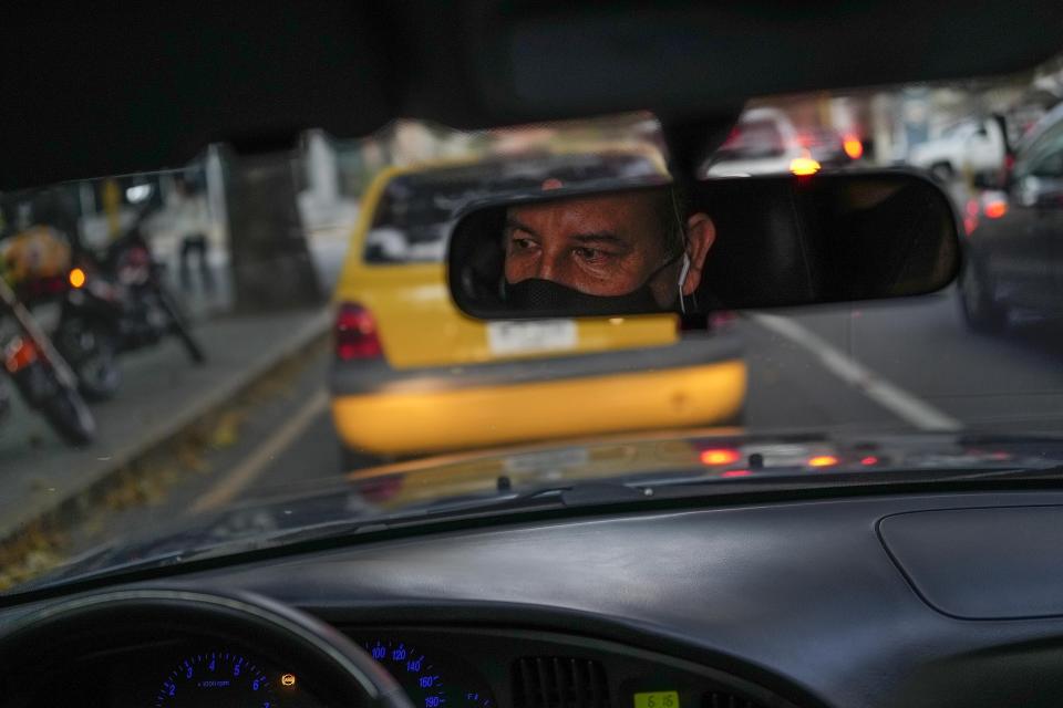 El conductor de la empresa de taxis por app Ridery, Marcelo Sánchez, se ve reflejado en el espejo retrovisor de su automóvil en Caracas, el jueves 5 de mayo de 2022. (AP Foto/Matias Delacroix)