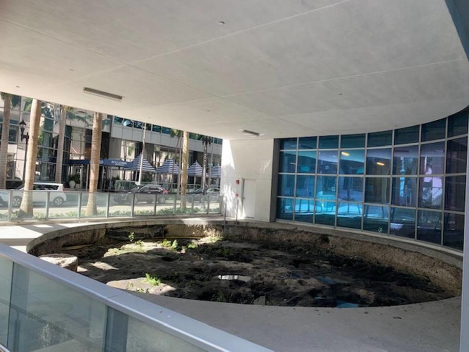 Un antiguo círculo tequesta de agujeros para postes conservado que el urbanizador MDM prometió encerrar en vidrio y exhibir en su complejo MetSquare permanece abierto al aire libre sin señalización que indique su importancia. La ciudad de Miami dice que la falta de un recinto viola un acuerdo legal de 2014.