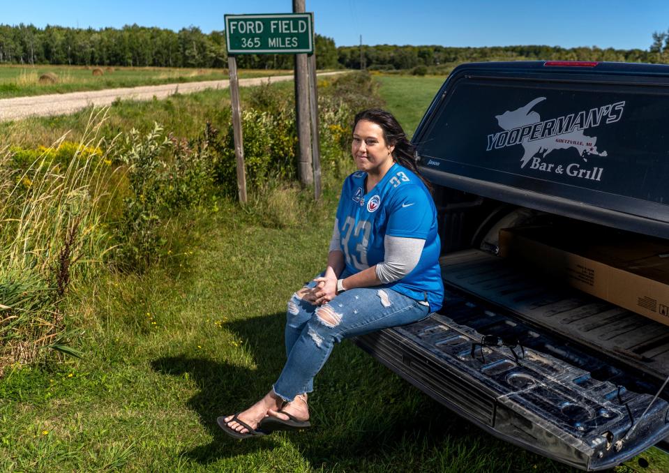 Detroit Lions superfan Megan "Yoopergirl" Stefanski sits on the tailgate of her father's truck, next to a sign he made noting the distance from his house to Ford Field in Detroit, a trip he made for every Lions home game for 25 years, on Wednesday, Aug. 30, 2023.