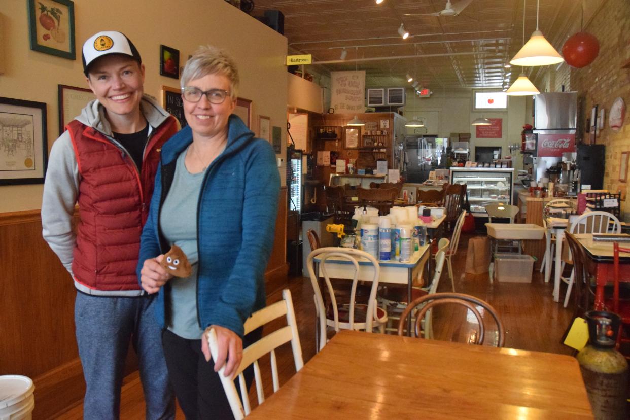 Julie Adams (right) and Cally Plummer (left) stand in the dining area of Julienne Tomatoes on Wednesday, May 18, over a week after the sewer backup damaged the restaurant's basement. As a way of finding humor in the situation, Adams asked to hold an emoji plush that she had in the restaurant in the picture.