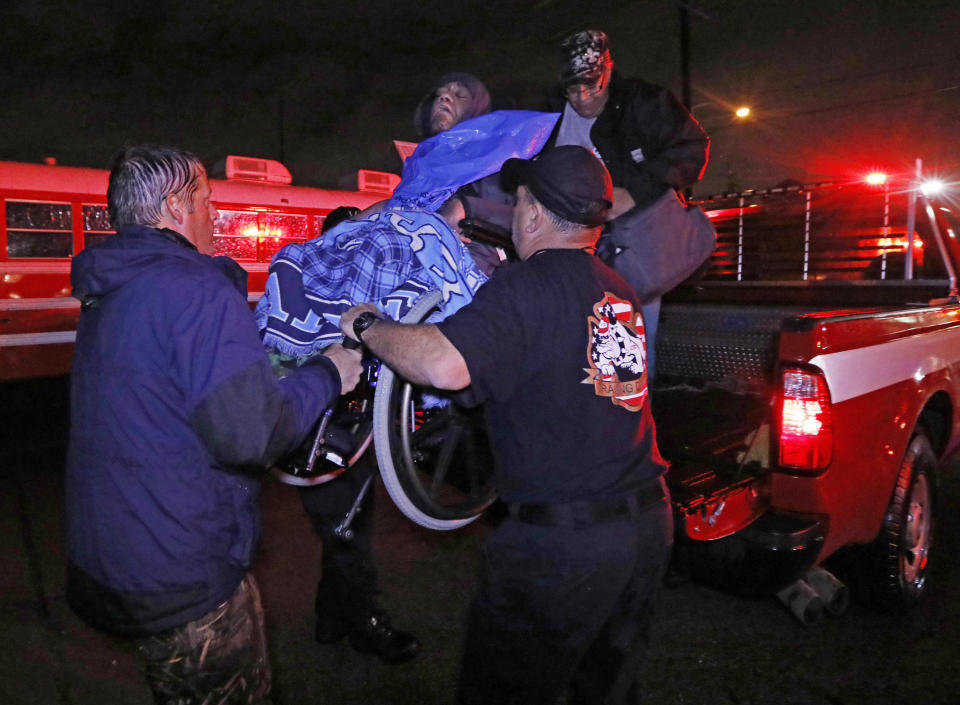 Lake Charles rescue personnel help lower this wheelchair bound resident from the back of a vehicle late Monday night, Aug. 28, 2017, in Lake Charles, La., after flooding from Harvey’s almost constant rain over the last two days overcame the city’s drainage system, flooding several subdivisions and necessitating home rescues. (AP Photo/Rogelio V. Solis)