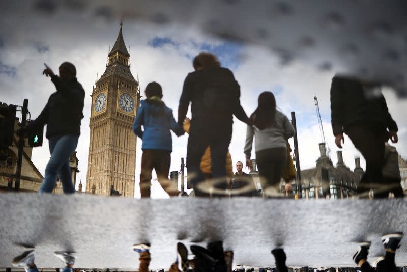 FILE PHOTO: The Elizabeth Tower, more commonly known as Big Ben, is seen reflected in a puddle as people walk outside the Houses of Parliament in London