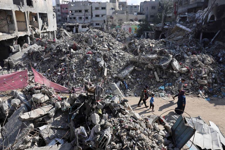 Las personas caminan frente a edificios destruidos después del bombardeo israelí en Gaza, en Bureij en el centro de la Franja de Gaza, el 14 de noviembre de 2023.