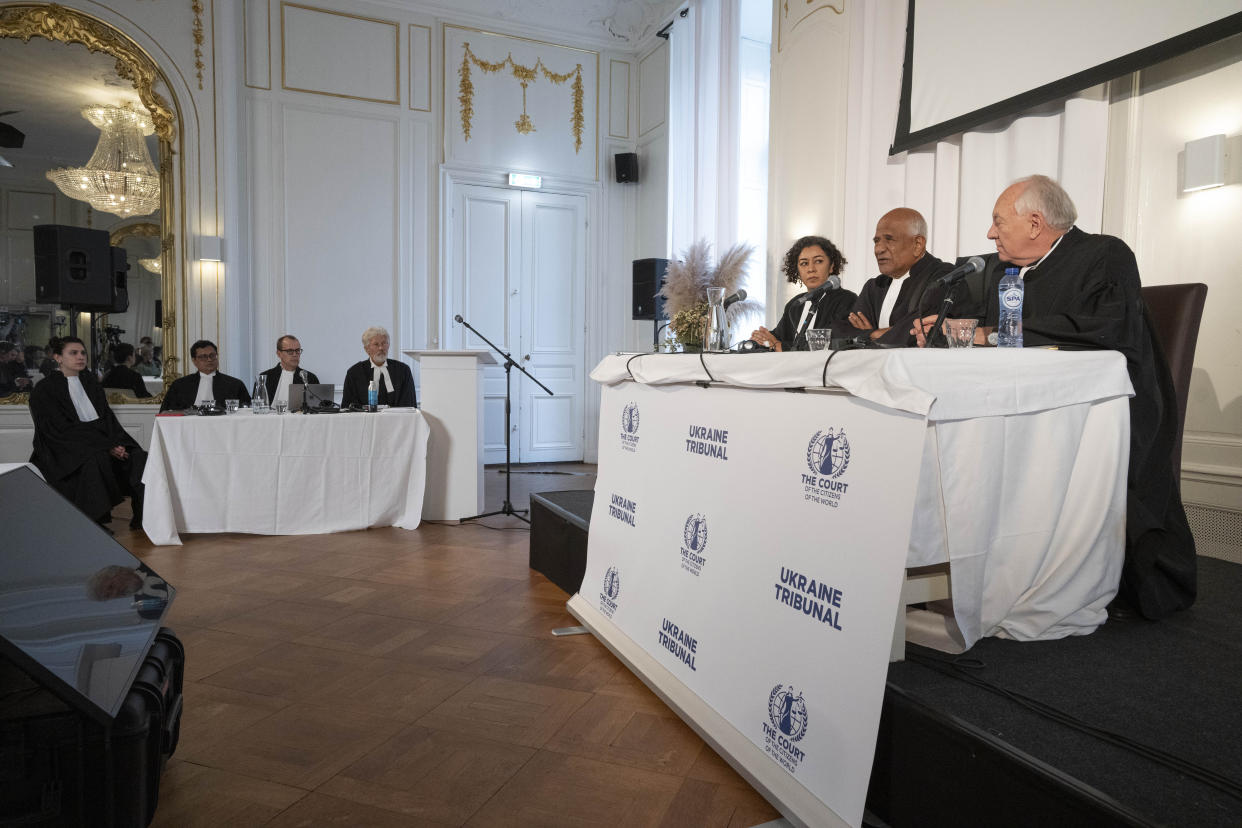 Judges Priya Pillai, third right, Zak Yacoob, second right, and Stephen Rapp, right, open the 'people's tribunal' where prosecutors Tapas K Baul, second left, David Akerson, third left, and Drew White, fourth left, symbolically put Russian President Vladimir Putin on trial for the crime of aggression in Ukraine, in The Hague, Netherlands, Monday, Feb. 20, 2023. (AP Photo/Peter Dejong)