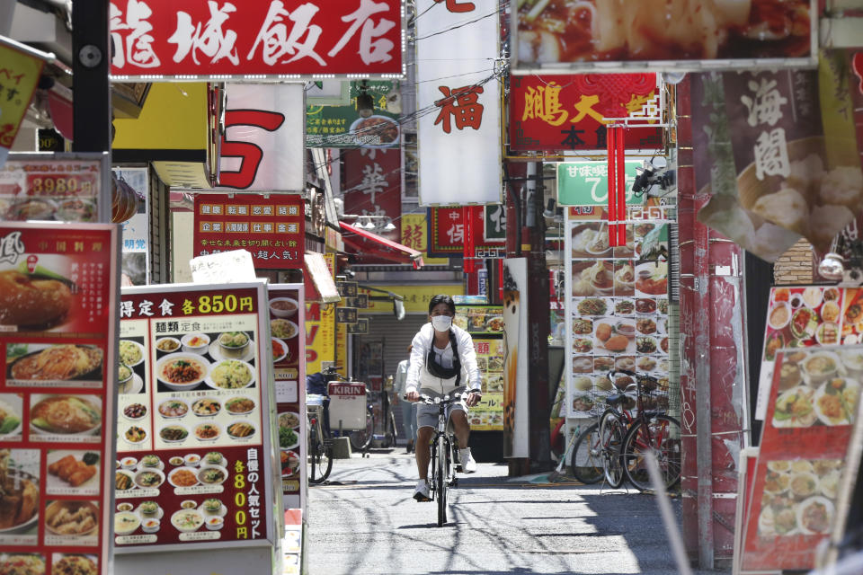 A man wearing a face mask to protect against the spread of the new coronavirus cycles through China Town in Yokohama, near Tokyo, Friday, May 8, 2020. Prime Minister Shinzo Abe announced that Japan extend a state of emergency until end of May. (AP Photo/Koji Sasahara)