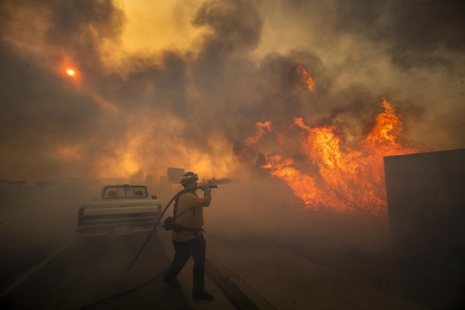 Firefighter Raymond Vasquez fights the Silverado fire fueled by Santa Ana winds at the 241 toll road