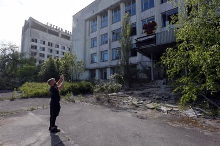 A visitor takes photos of a building in the abandoned city of Pripyat, near the Chernobyl nuclear power plant