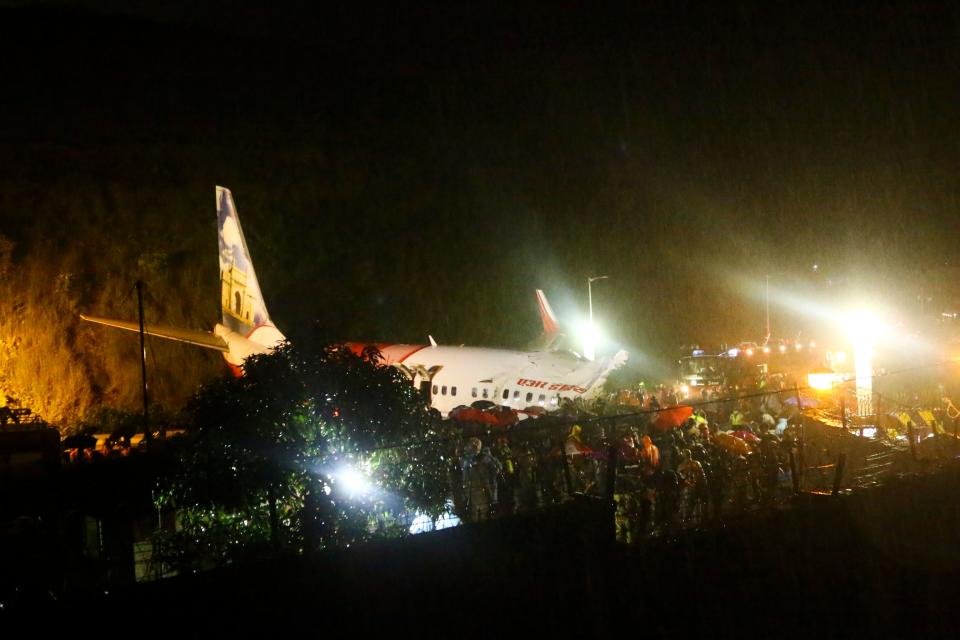 First responders gather around the wreckage of an Air India Express jet, which was carrying more than 190 passengers and crew from Dubai, after it crashed by overshooting the runway at Calicut International Airport in Karipur, Kerala, on August 7, 2020. - At least 14 people died and 15 others were critically injured when a passenger jet skidded off the runway after landing in heavy rain in India, police said on August 7. (Photo by Favas JALLA / AFP) (Photo by FAVAS JALLA/AFP via Getty Images)