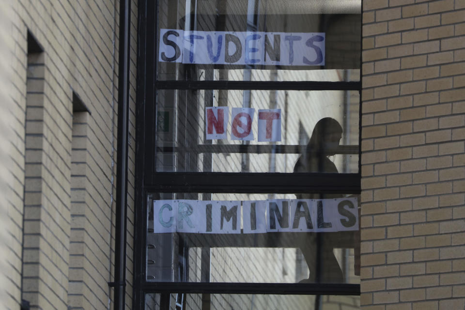 A student walks past a sign at Murano Street Student Village in Glasgow, where Glasgow University students are being tested at a pop up test centre, Scotland, Friday, Sept. 25, 2020. Cities around the U.K. are imposing new coronavirus restrictions as they race to slow the spread of COVID-19, and London could be next. University students in Scotland were asked not to go to bars and restaurants this weekend. (Andrew Milligan/PA via AP)