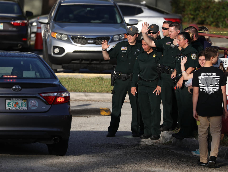 Broward County Sheriff officers wave as they welcome students as they arrive.