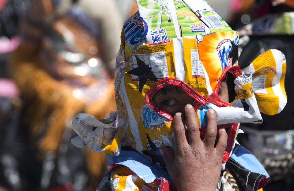 Un niño interpreta un baile mientras usa una máscara hecha con material reciclado durante un festival de danzas folclóricas y autóctonas para crear conciencia ambiental en El Alto, Bolivia, el martes 14 de agosto de 2018. (AP Foto/Juan Karita)