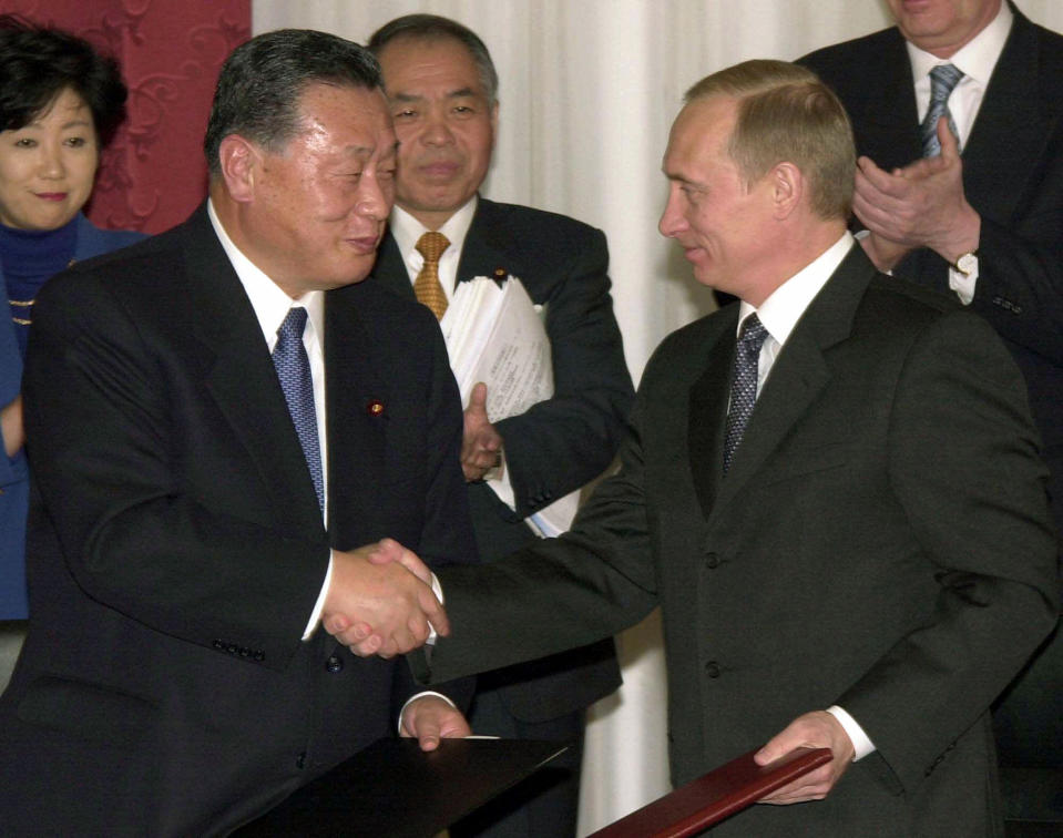 FILE - In this March 25, 2001, Russian President Vladimir Putin, right, shakes hands with Japanese Prime Minister Yoshiro Mori, second left, accompanied by Japanese lawmakers, Yuriko Koike, left, and Muneo Suzuki, after a signing ceremony of "Irkutsk Declaration" at Baikal Business Center in Irkutsk, Russia. Japan and the former Soviet Union restored diplomatic relations a decade after World War II, but a dispute over a cluster of islands kept them from signing a peace treaty. Russian President Vladimir Putin is in Japan on Thursday, Dec. 15, 2016 for a two-day talks with Japanese Prime Minister Shinzo Abe on the issue. (AP Photo/Koji Sasahara, File)