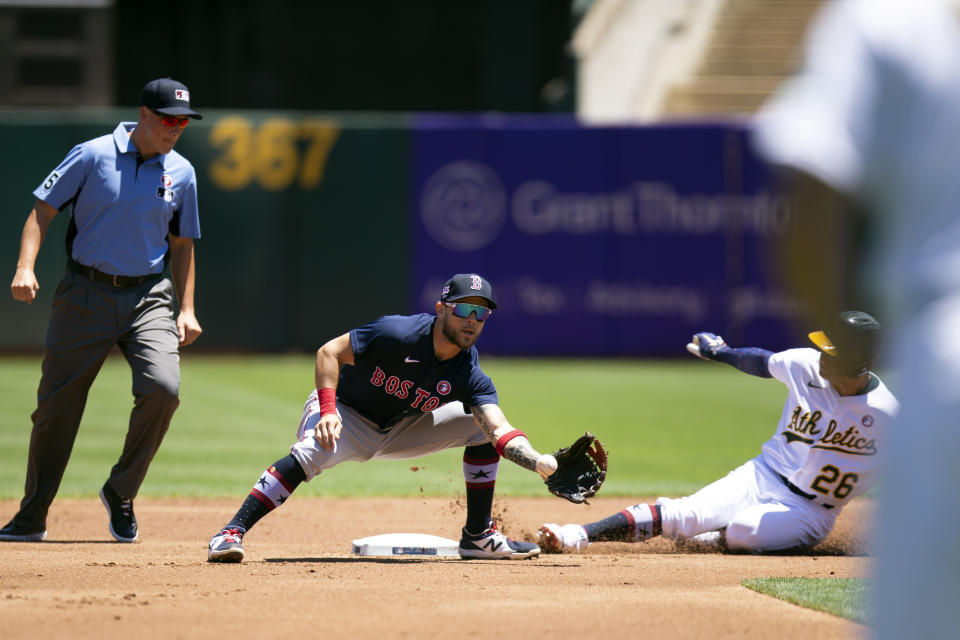 Oakland Athletics' Matt Chapman (26) slides safely into second base with a double ahead of the relay to Boston Red Sox second baseman Michael Chavis, center, during the first inning of a baseball game, Sunday, July 4, 2021, in Oakland, Calif. Umpire is Stu Scheurwater, left, looks on. (AP Photo/D. Ross Cameron)