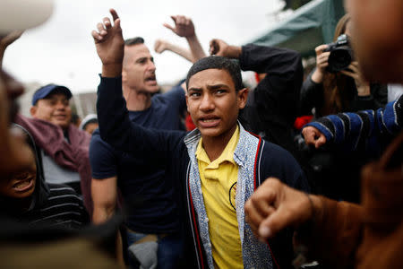 Members of a caravan of migrants from Central America react near the San Ysidro checkpoint as the first fellow migrants entered U.S. territory to seek asylum on Monday, in Tijuana, Mexico April 30, 2018. REUTERS/Edgard Garrido