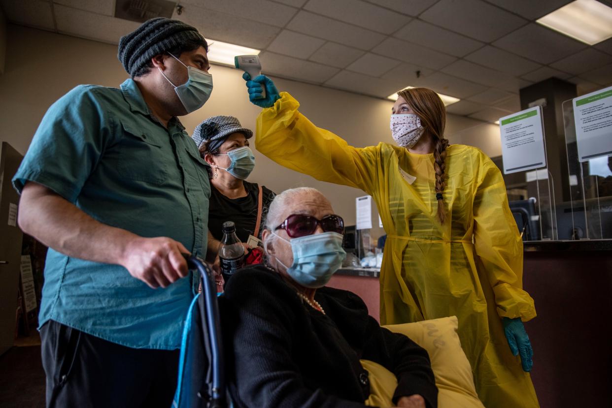 Kelly Russell takes the temperature of a patient at a vaccination site at a senior center on March 29, 2021, in San Antonio, Texas.