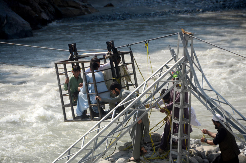 People are helped across a flood disaster area in Swat