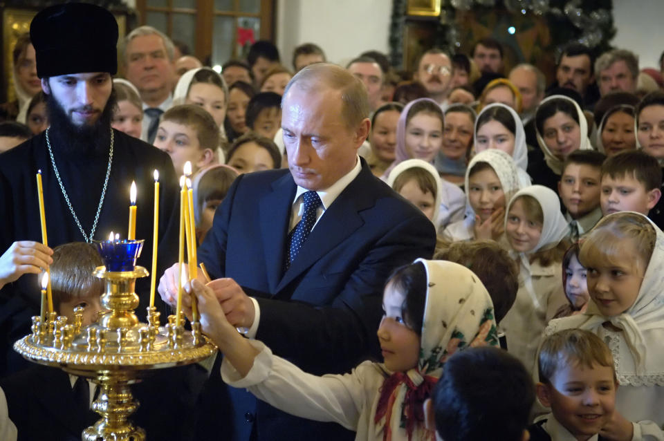 FILE - Russian President Vladimir Putin, center, surrounded by children, lights a candle during Russian Orthodox Christmas celebrations in a cathedral in the Siberian city of Yakutsk, on Jan. 6, 2006. Although abortion in Russia is still legal and widely available, new restrictions are being considered as Putin takes an increasingly socially conservative turn and seeks to reverse the country's declining population. (Sergei Guneyev, Sputnik, Kremlin Pool Photo via AP, File)