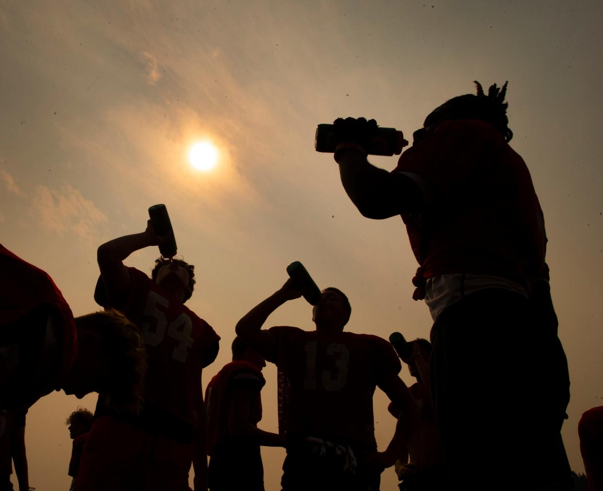 Thurston football players take a water break during practice in Springfield as temperatures drop and smoky skies begin to clear Monday morning.