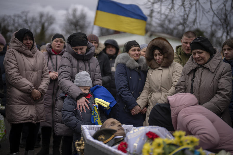 FILE - Tymofii, 5, cries with his mother Alla, next to the body of his father Kostiantyn, 35, during his funeral in Borova, near Kyiv, Ukraine, Saturday, Feb. 18, 2023. Kostiantyn Kostiuk, a civilian who was a volunteer in the armed forces of Ukraine, was wounded during a battle against Russians on Jan. 23rd near Bakhmut and finally died on Feb. 10th in a hospital. (AP Photo/Emilio Morenatti, File)