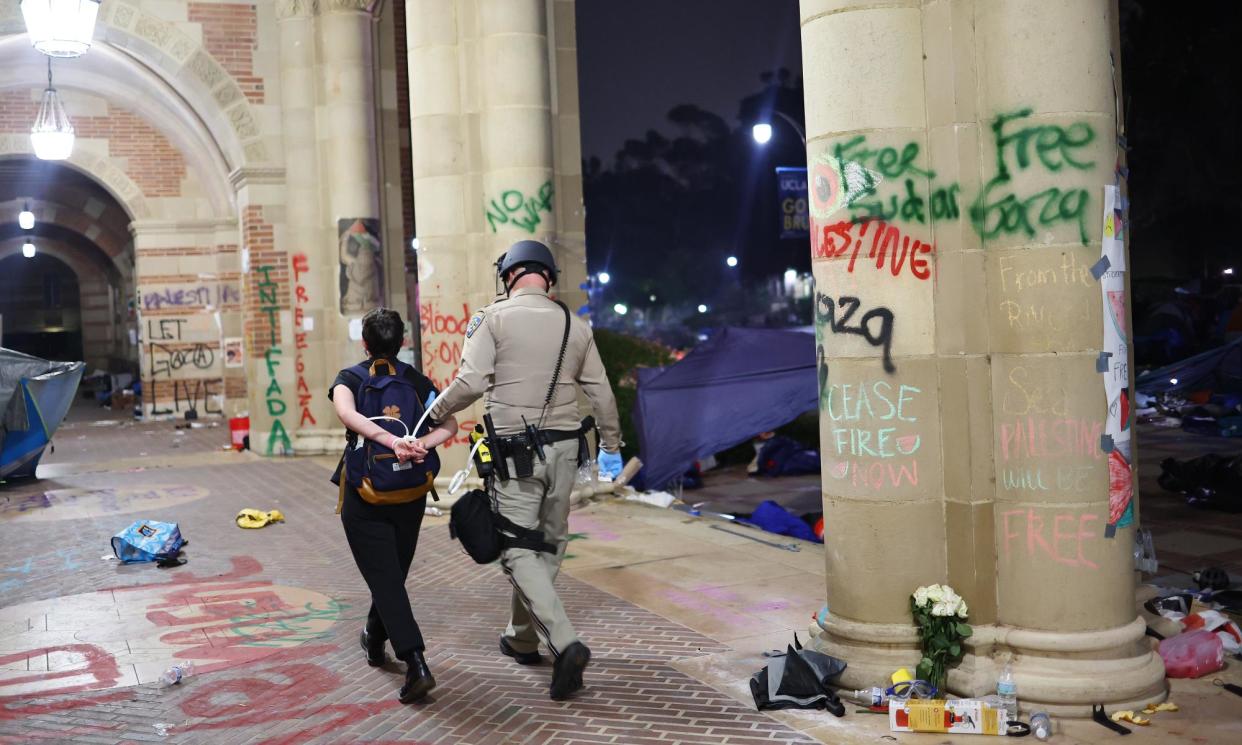 <span>A California highway patrol (CHP) officer detains a protester while clearing a pro-Palestinian encampment at UCLA on 2 May 2024, in Los Angeles, California.</span><span>Photograph: Mario Tama/Getty Images</span>