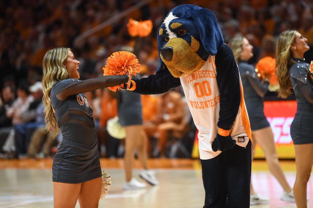 A cheerleader fist bumps Smokey at Thompson-Boling Arena at Food City Center in Knoxville.