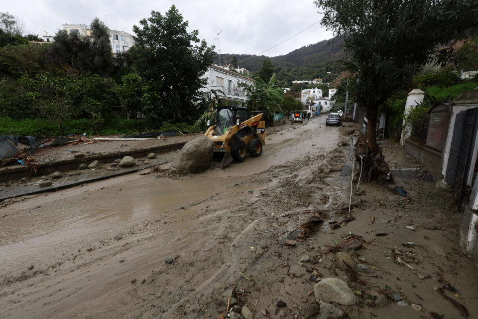 Rescuers remove mud from a street after heavy rainfall triggered landslides that collapsed buildings and left as many as 12 people missing, in Casamicciola, on the southern Italian island of Ischia, Italy, Saturday, Nov. 26, 2022. Firefighters are working on rescue efforts as reinforcements are being sent from nearby Naples, but are encountering difficulties in reaching the island either by motorboat or helicopter due to the weather. (Alessandro Garofalo/LaPresse via AP)