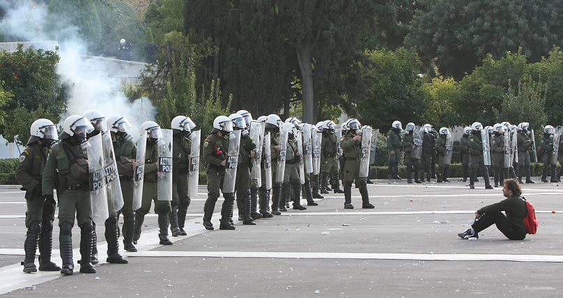 A protester sits on the ground in front of riot police in central Athens on Tuesday, Dec. 9, 2008.