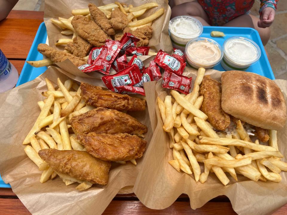 A tray overflowing with french fries, fried fish, fried chicken, and a fried fish sandwich.