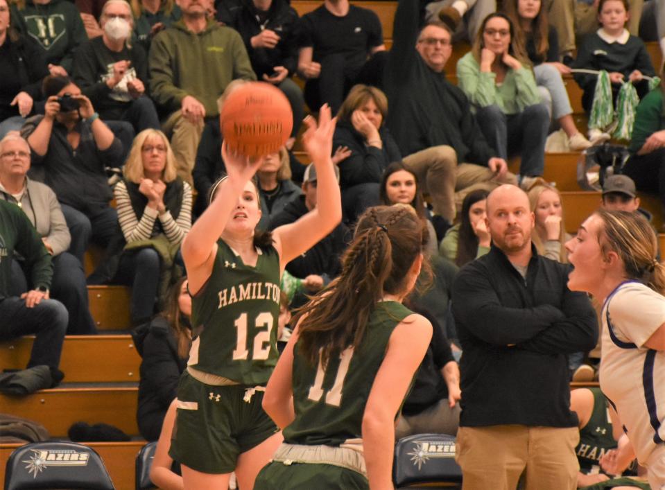 Reagan Hope (12) shoots a three-pointer in front of the Hamilton bench and coach Joe LePage during the second half of the Emerald Knights' Section III semifinal against West Canada Valley.
